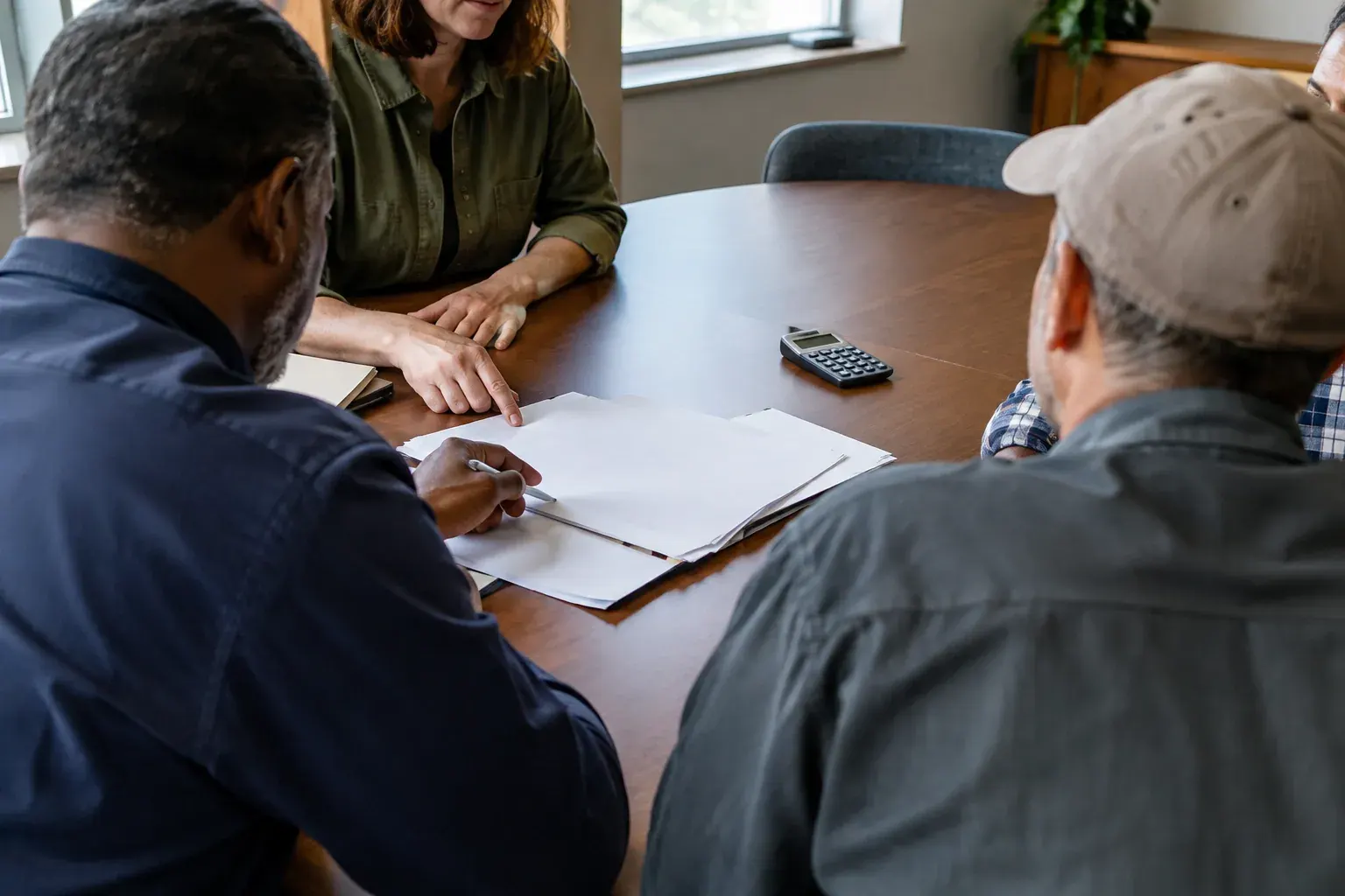 Workers review a contract together at a meeting table.