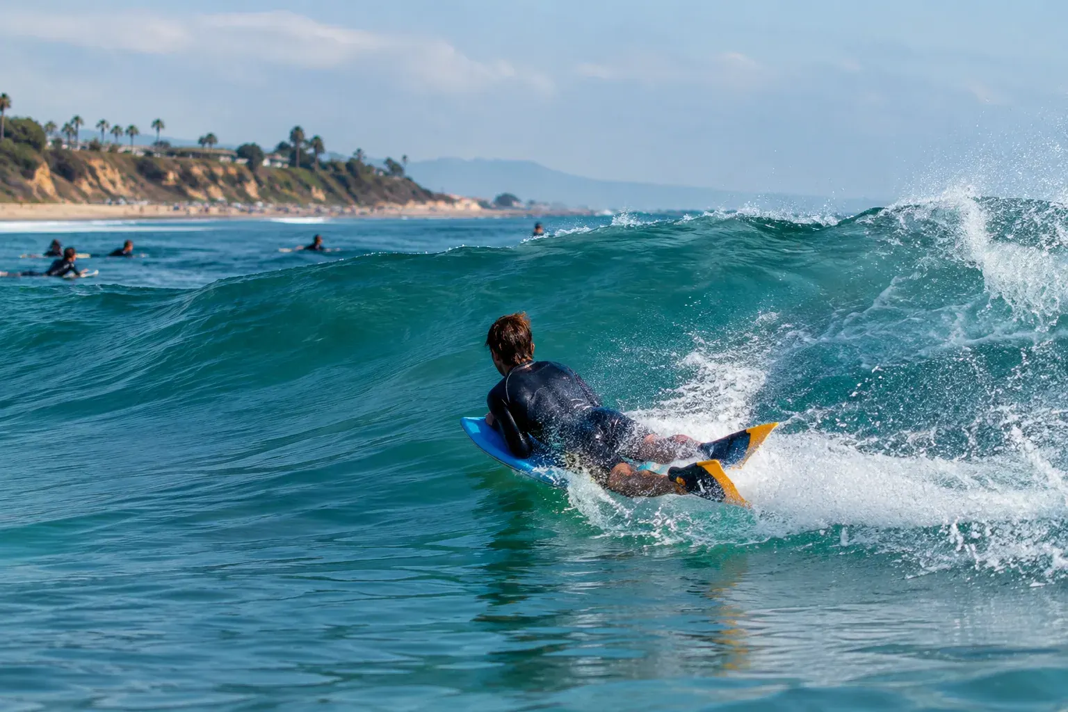 A bodyboarder rides a breaking wave during a beach competition.